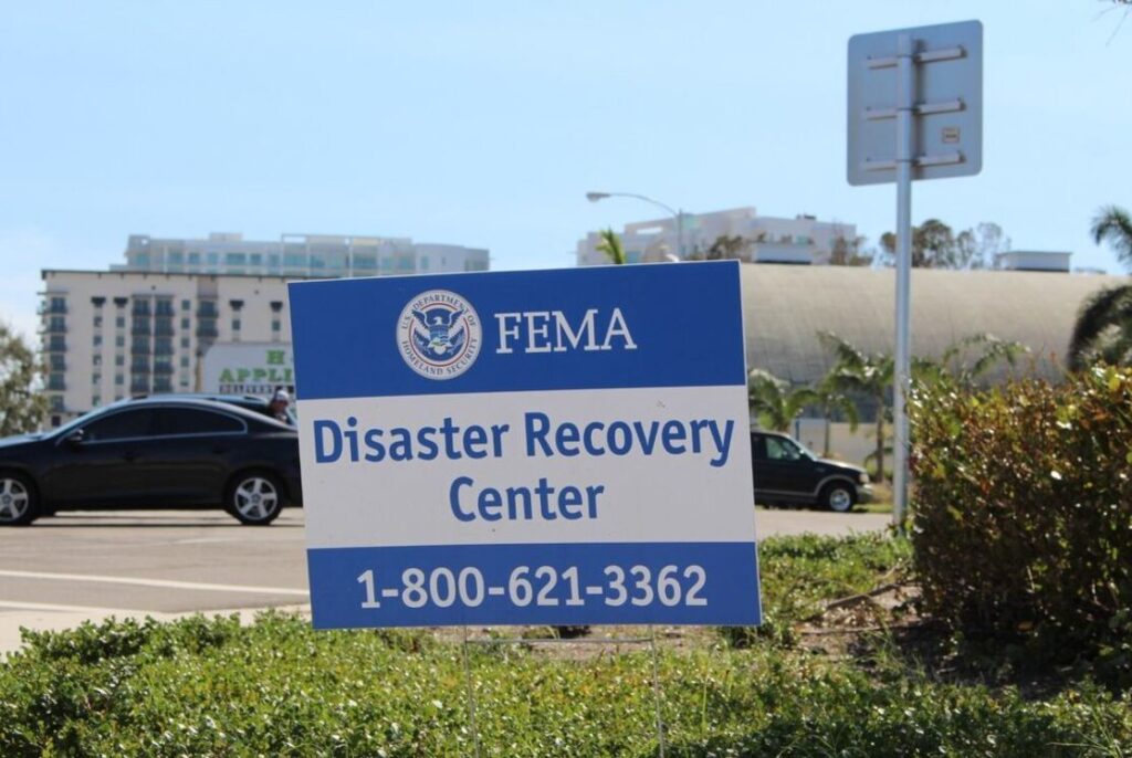 A sign by the road that reads "FEMA Disaster Recovery Center" with the phone number 1-800-621-3362.