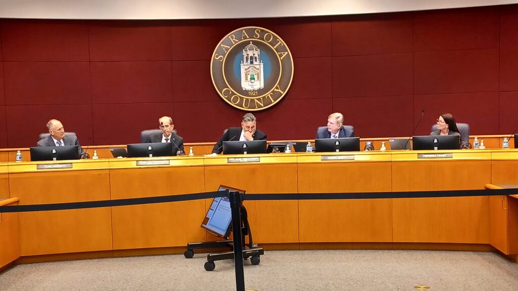 The five county commissioners sit at the front of the commission chamber.