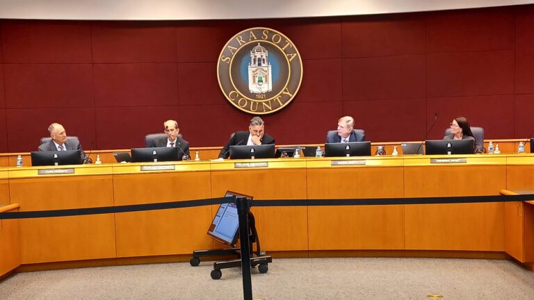 The five county commissioners sit at the front of the commission chamber.