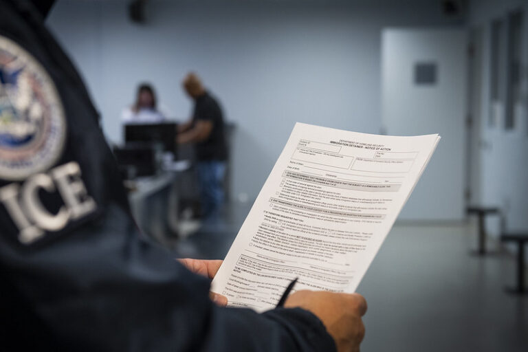 ICE officer holding a blank Form I-247A.