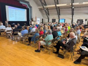 A full crowd watches as a presenter speaks in front of a slide titled "Consolidated income statement."