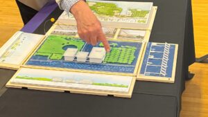 An unseen person points at part of a scale model of the proposed performing arts center.