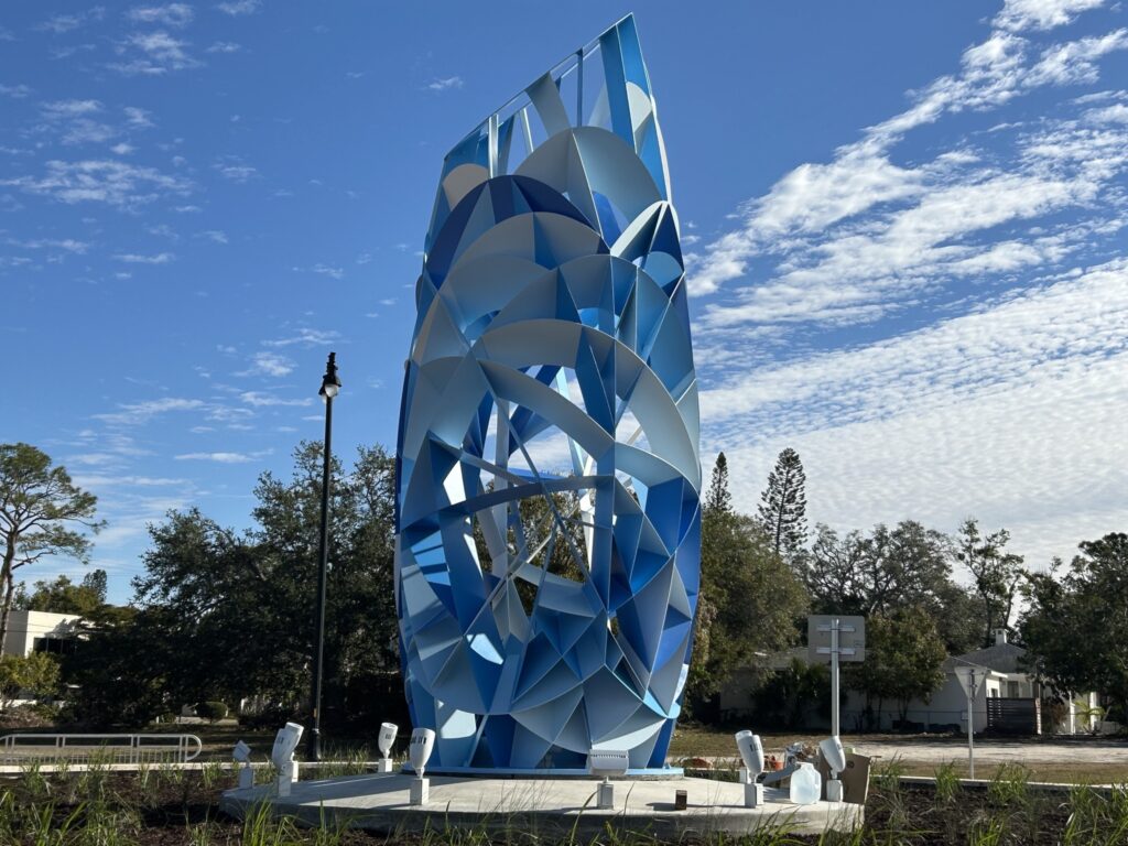 Photo of a 20-foot blue cylindrical abstract sculpture in the center of a roundabout.