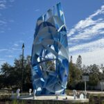 Photo of a 20-foot blue cylindrical abstract sculpture in the center of a roundabout.