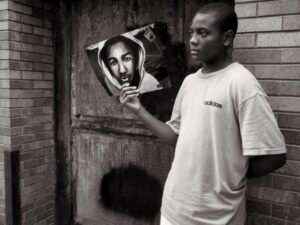 Photo of a Black man holding a portrait of Trayvon Martin.