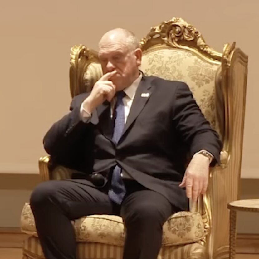 Tom Homan sitting in an ornate golden chair on stage.