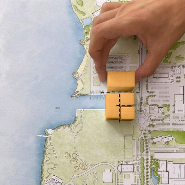Someone's hand is shown manipulating model buildings atop a map of the area around the proposed performing arts center