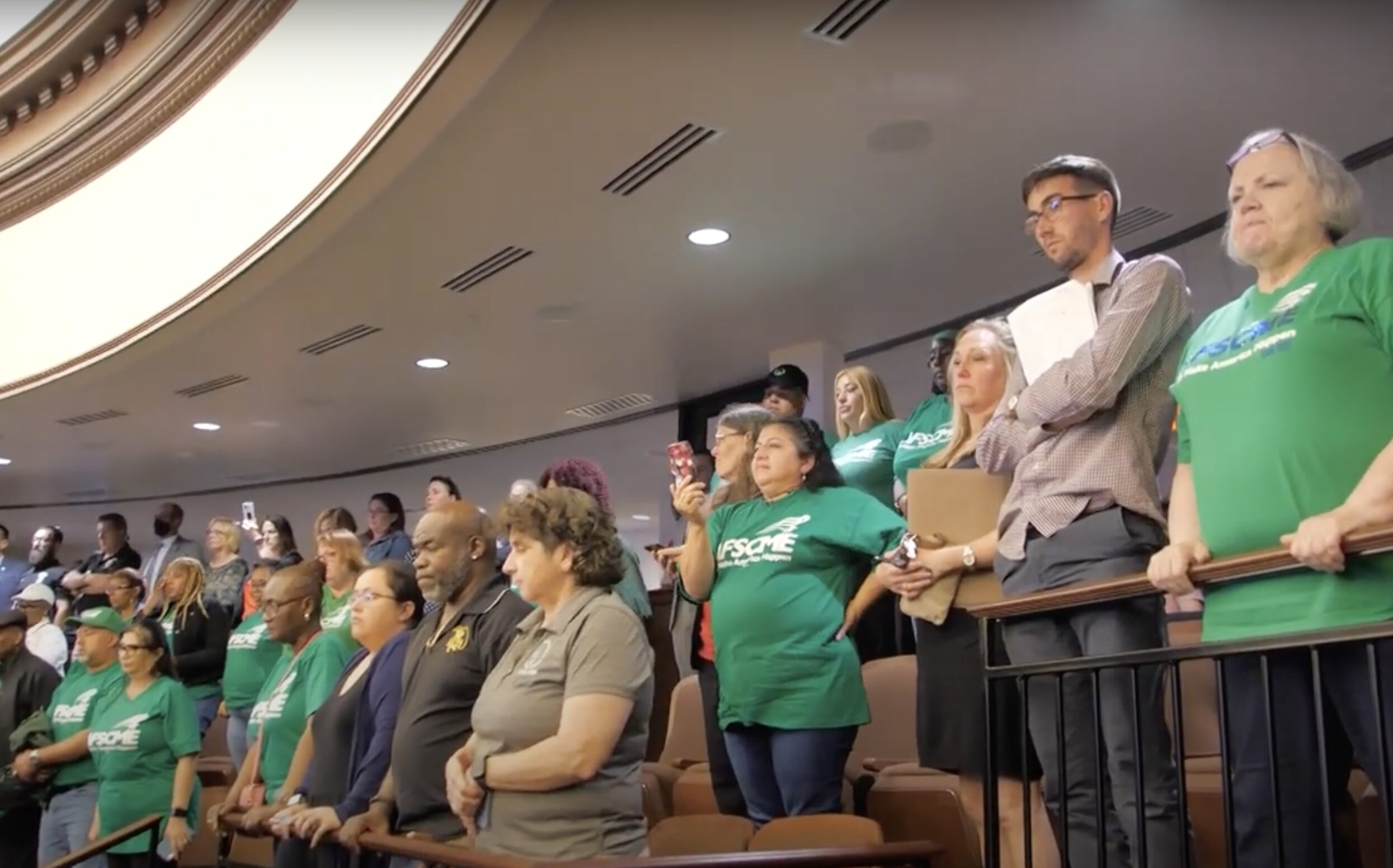 Shot of the audience at the State Capitol. Many members are wearing green AFSCME t-shirts.