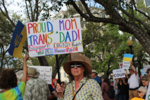 A protester holds up a sign that reads "Proud mom of a trans dad! Support LGBTQ+ Rights! ...and ALL Human Rights!