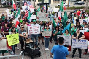 A crowd of pro-immigrant demonstrators holding signs such as "Speak for those who can't!" and "Stop separating families".