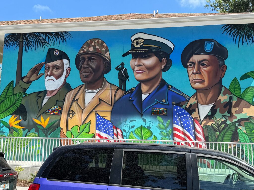 Painted mural on the side of a building featuring busts of four members of the United States armed forces.