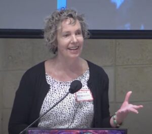 Jennifer Berkshire speaks into a microphone, smiling.