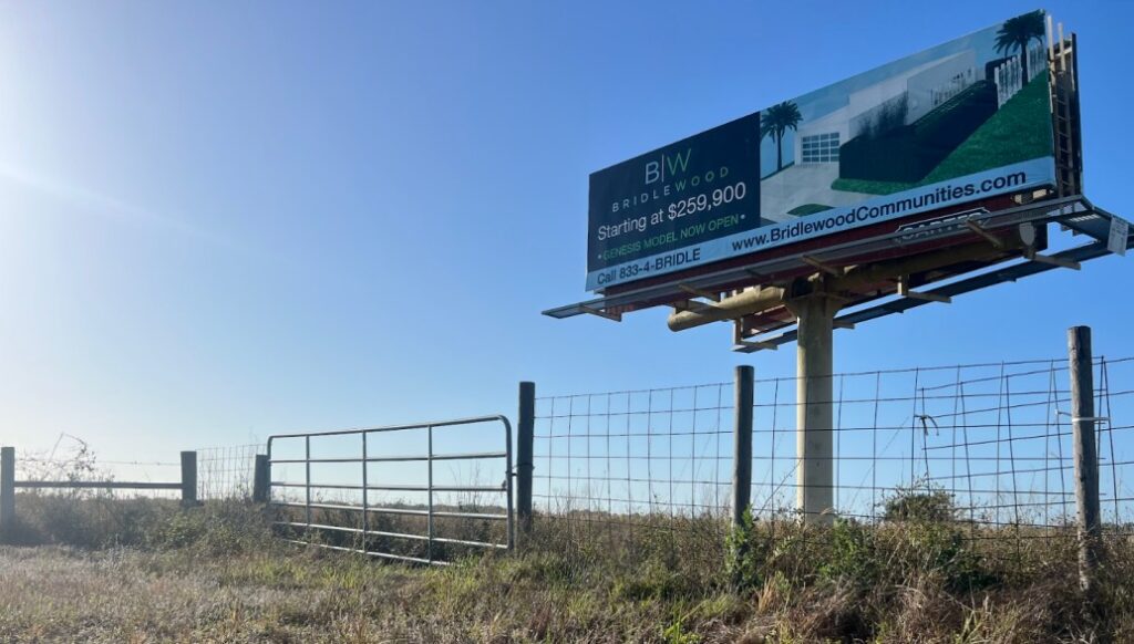 A billboard for Bridlewood, "Starting at $259,000." advertising that their "Genesis model" is "now open."