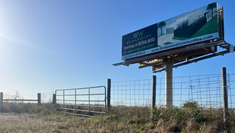 A billboard for Bridlewood, "Starting at $259,000." advertising that their "Genesis model" is "now open."