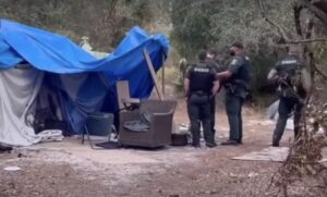 Police officers stand near a makeshift tent.