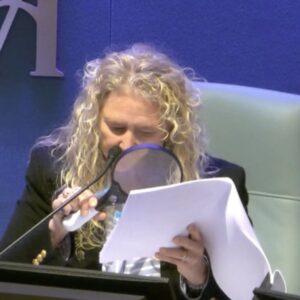 City commissioner Jen Ahearn-Koch reviews documents with a large magnifying glass.