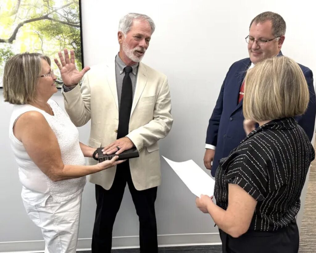Lloyd Weed swearing in, one hand on the Bible.