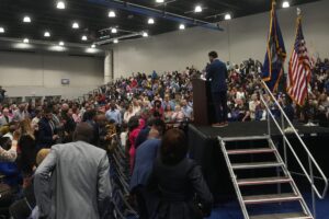 Max Frost addressing a packed crowd at a town hall.