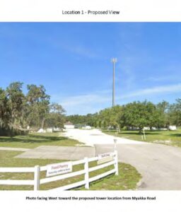 Photo a stretch of of Myakka Road. A mockup of the proposed cell tower places it high over the treetops. Top text: Location 1 - Proposed View Bottom text: Photo facing West toward the proposed tower location from Myakka Road
