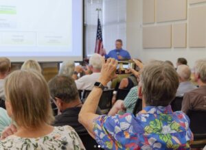 An audience member takes a picture with their phone of a PowerPoint slide during a presentation.