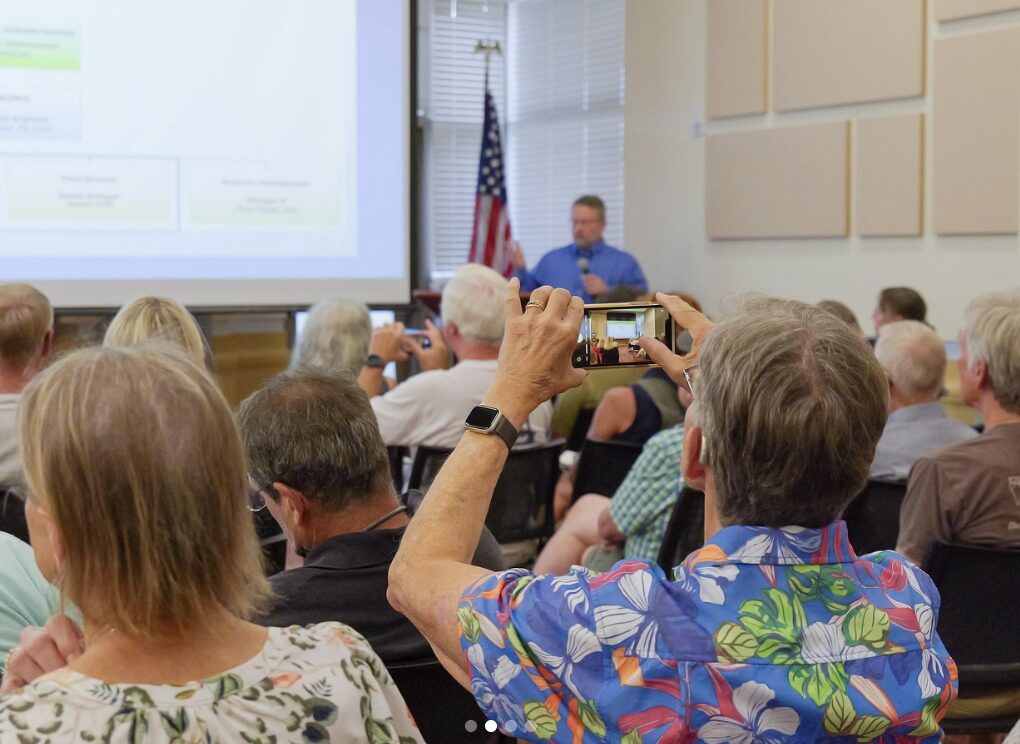 An audience member takes a picture with their phone of a PowerPoint slide during a presentation.