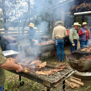 Photo of people grilling outdoors. All subjects are wearing cowboy hats.
