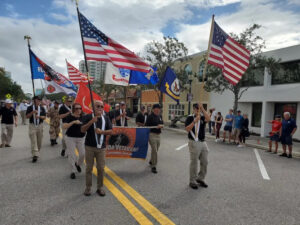 Demonstrators march holding U.S. flags and Florida Veterans for Common Sense flags.
