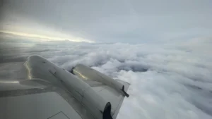 Shot of the wing of a plane flying above the clouds.