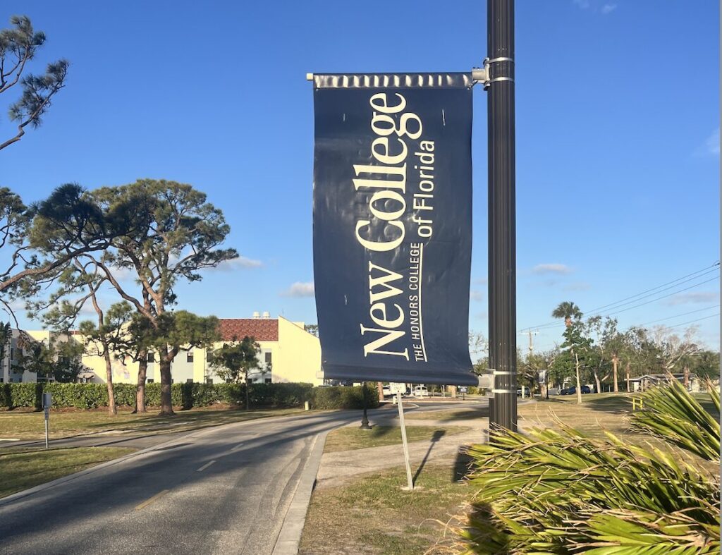 A New COllege of Florida banner waving from a post by the road.