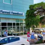 A handful of picketers outside a Planned Parenthood clinic.Some hold signs that read "Pray to end abortion".