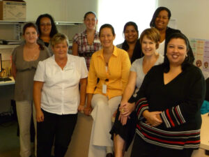 A photo of a group of people in a doctor's office posing for the picture and smiling.