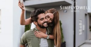 Photo featuring a couple embracing happily in front of a contemporary home. One of them holds a key. In the top right is text which reads "SimplyDwell Homes."