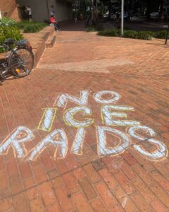 Bold chalk letters on a brick walkway: "No ICE raids".