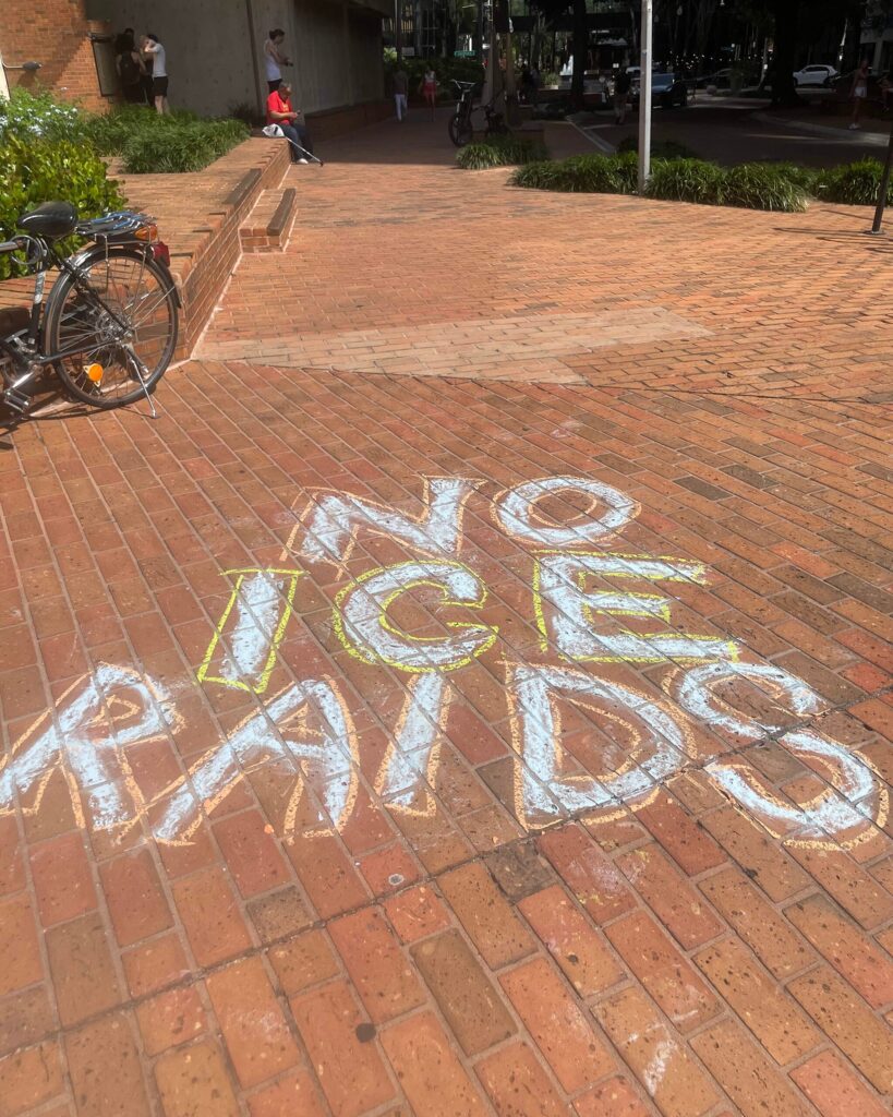 Bold chalk letters on a brick walkway: "No ICE raids".