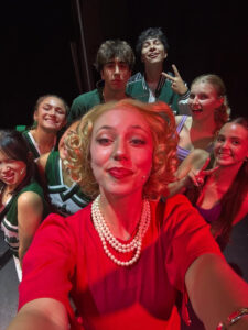 Selfie taken in bright red light featuring eight enthusiastic performers.