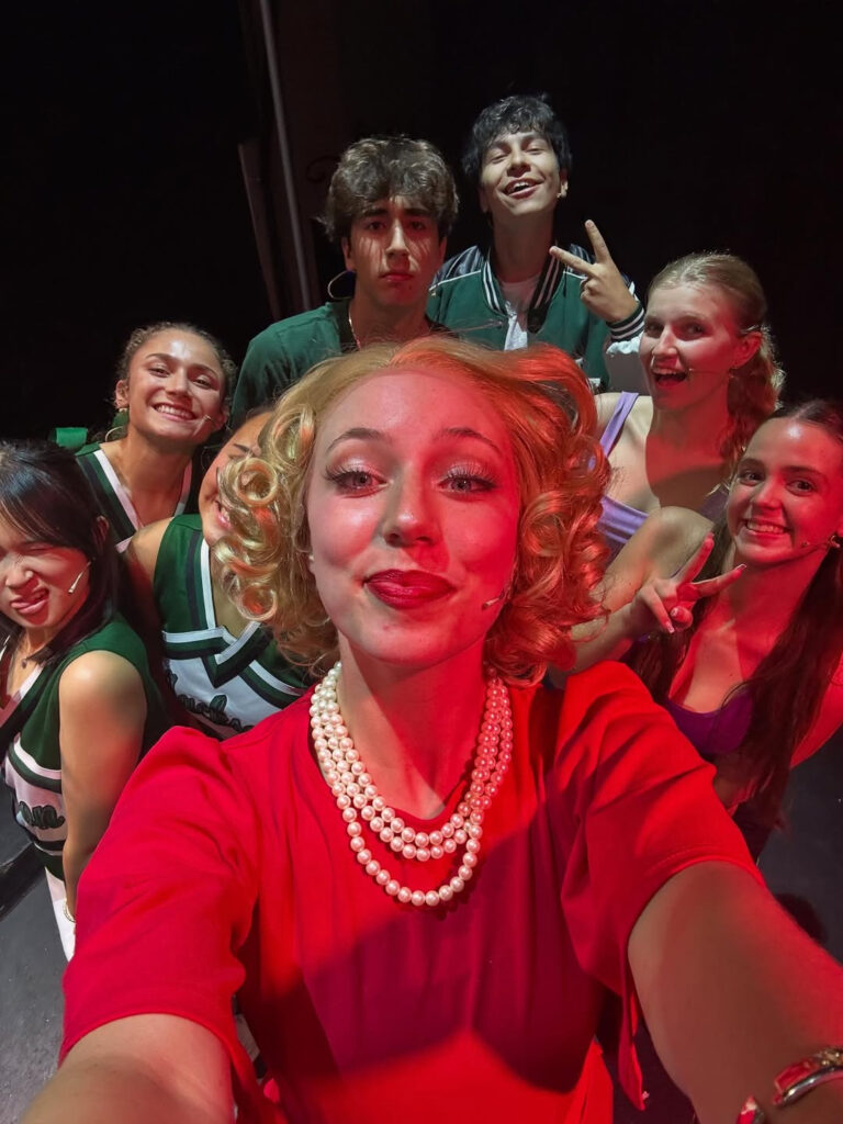 Selfie taken in bright red light featuring eight enthusiastic performers.