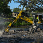 Photo of sediment being removed from a creek by an excavator.