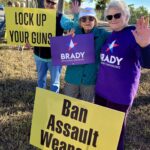 Three demonstrators hold anti-gun violence protest signs and Brady paraphernalia.