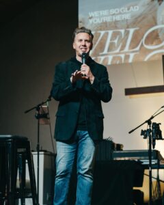 Brian Gibbs on stage with a microphone.