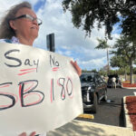 A demonstrator holds a handwritten sign that reads "Say no to SB 180."