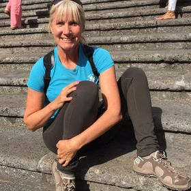 Denise Kowal smiling while sitting on a staircase outdoors.