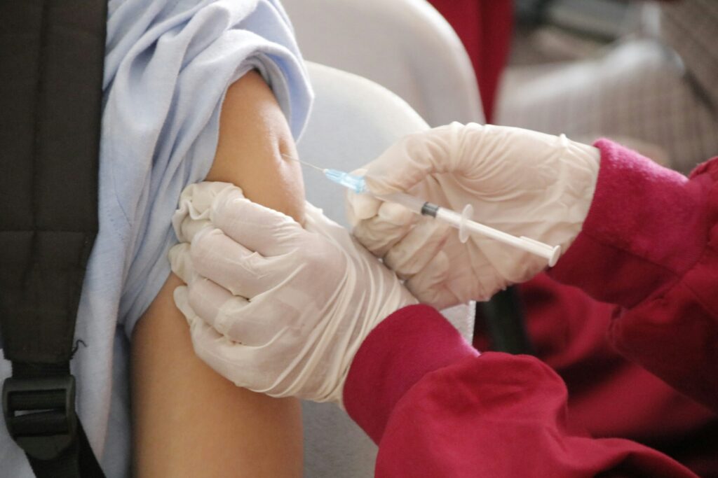 Extreme close-up of a health professional administering a vaccine to a patient.