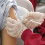 Extreme close-up of a health professional administering a vaccine to a patient.