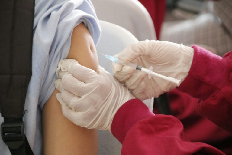 Extreme close-up of a health professional administering a vaccine to a patient.
