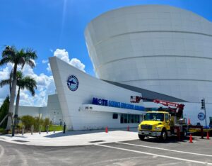 Photo of a truck with a boom lift outside the front of the new Mote Marine Science Education Aquarium facility, a large modern building.