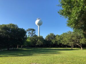 Photo of a distant water tower viewed from a grassy clearing.