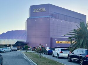 Photo of cars lined up outside the Van Wezel Performing Arts Hall, a striking purple building.
