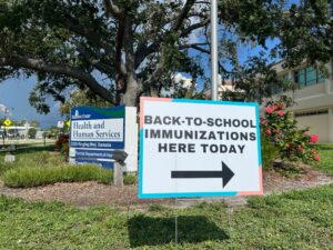 Sign with arrow that reads "Back-to-school immunizations here today" outside the Sarasota County Health and Human Services building.
