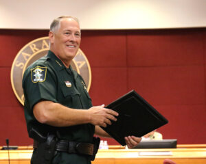 Tom Knight smiling, holding a frame that faces away from the camera.