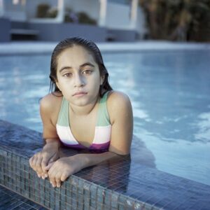 Photo of a young girl in a swimming pool facing the viewer.